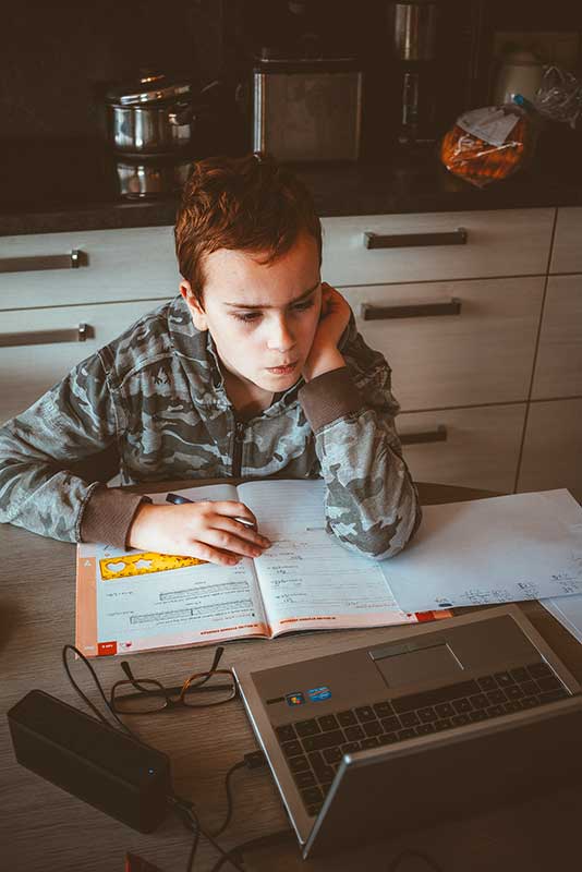 poika opiskelee kotona matematiikkaa